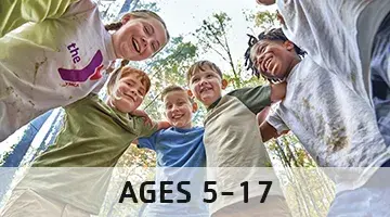 Group of kids arm in arm standing in a circle. There's an overlay on the bottom that says ages 5-17 indicating the age group that camp is geared toward. 